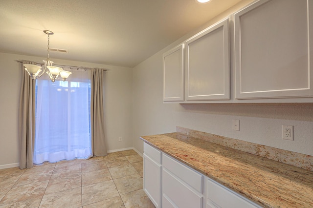 kitchen featuring pendant lighting, white cabinetry, a chandelier, light tile patterned floors, and light stone countertops