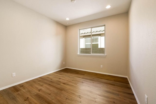 unfurnished room featuring recessed lighting, wood finished floors, and baseboards