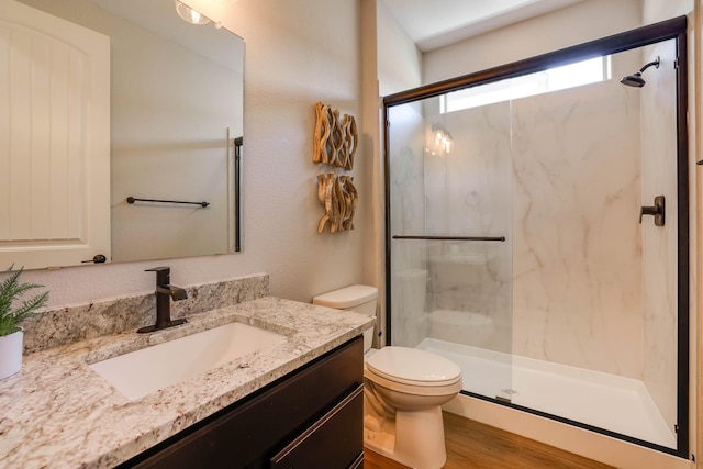 full bathroom featuring toilet, vanity, a marble finish shower, and wood finished floors