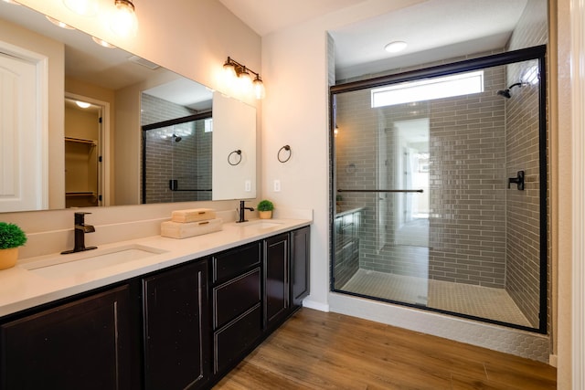 full bath with double vanity, a spacious closet, a sink, and wood finished floors