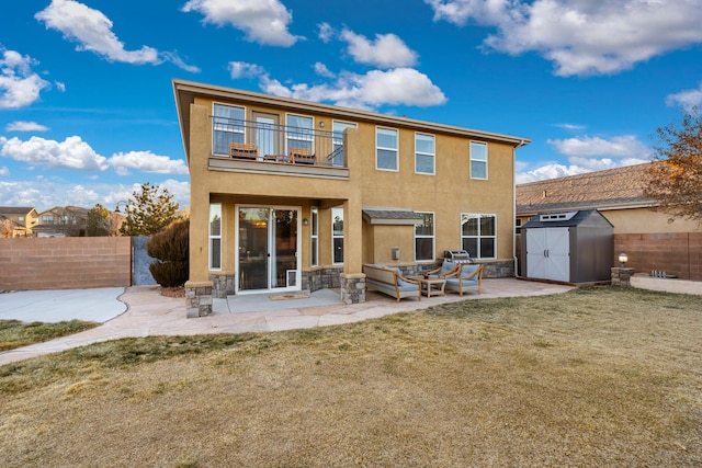 back of house with a balcony, a storage shed, a patio area, and a lawn