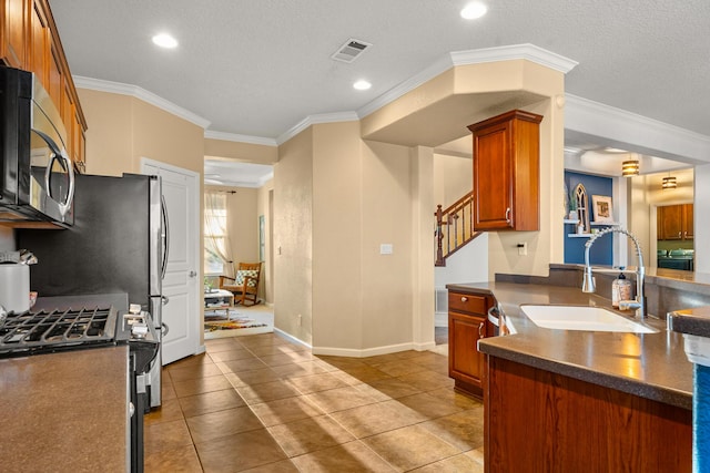 kitchen featuring sink, ornamental molding, a textured ceiling, and appliances with stainless steel finishes