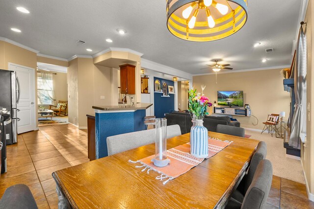 dining room featuring sink, a textured ceiling, light tile patterned floors, ornamental molding, and ceiling fan