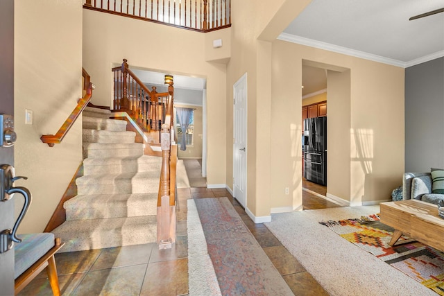 foyer featuring stairway, dark tile patterned floors, baseboards, and crown molding