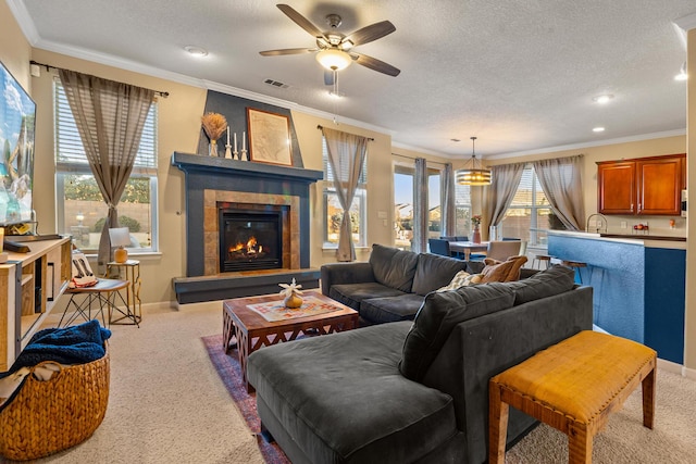 carpeted living room with ceiling fan, crown molding, a fireplace, and a textured ceiling