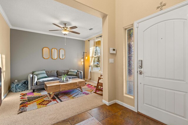 entryway featuring ceiling fan, ornamental molding, and a textured ceiling