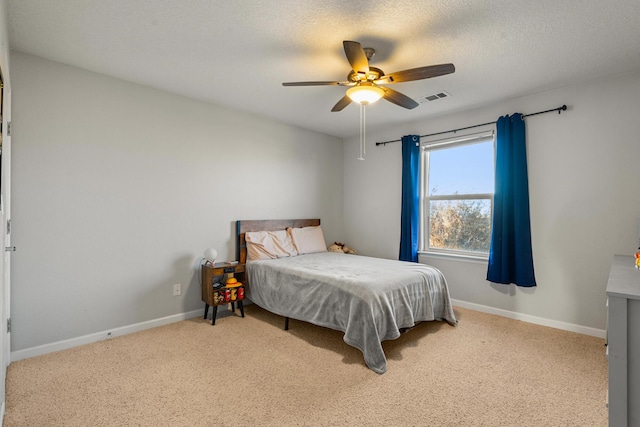 bedroom featuring ceiling fan, light colored carpet, and a textured ceiling