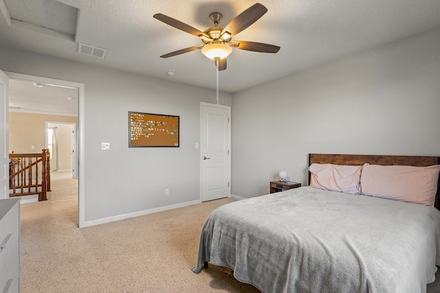 bedroom featuring ceiling fan, light colored carpet, and a textured ceiling