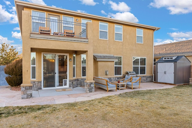 rear view of property with a patio, a balcony, a yard, and a storage shed