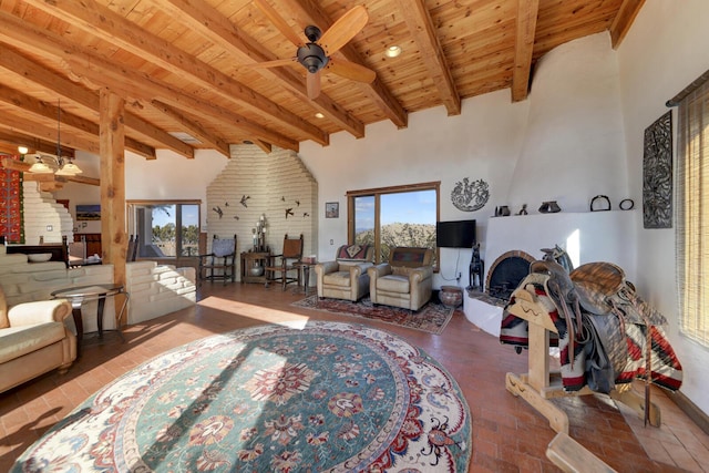 living room featuring ceiling fan, a towering ceiling, beam ceiling, wood ceiling, and a fireplace