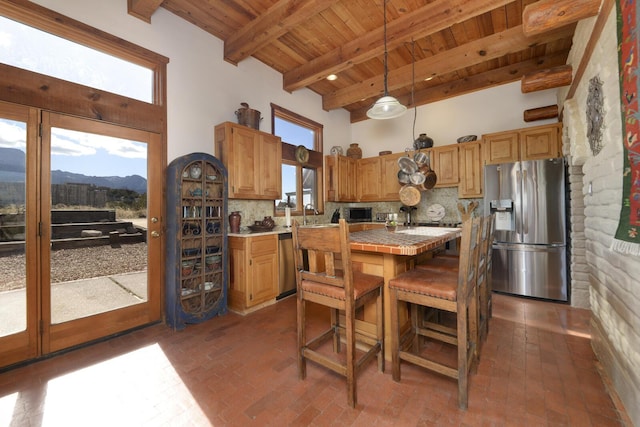 kitchen with decorative light fixtures, stainless steel appliances, beamed ceiling, backsplash, and a mountain view