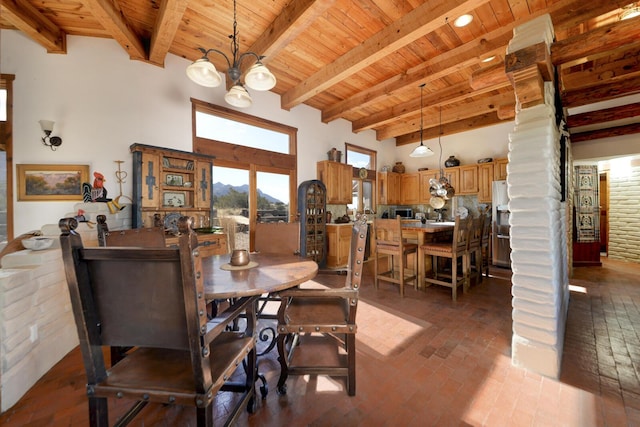 dining space with ornate columns, a towering ceiling, beam ceiling, wood ceiling, and an inviting chandelier