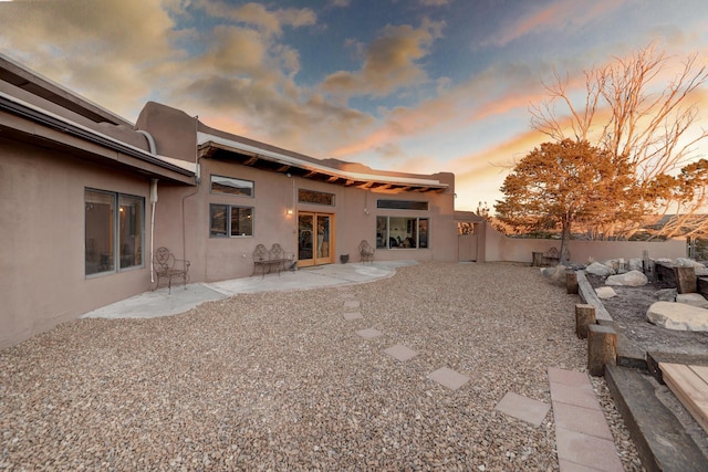 back house at dusk featuring a patio area