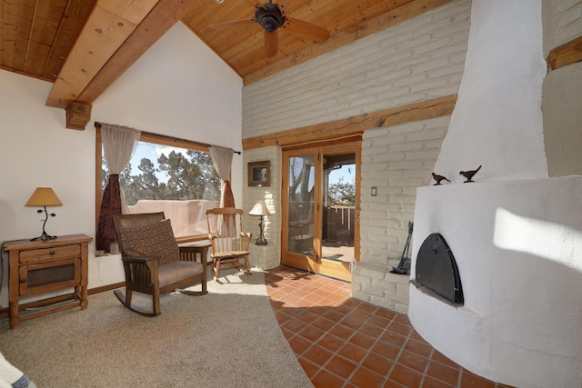 interior space with ceiling fan, a high ceiling, a brick fireplace, and wood ceiling