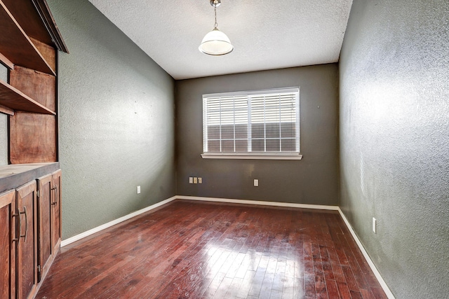 spare room featuring a textured ceiling and dark hardwood / wood-style flooring