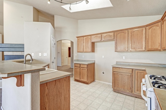 kitchen featuring white range with gas stovetop, a textured ceiling, and vaulted ceiling