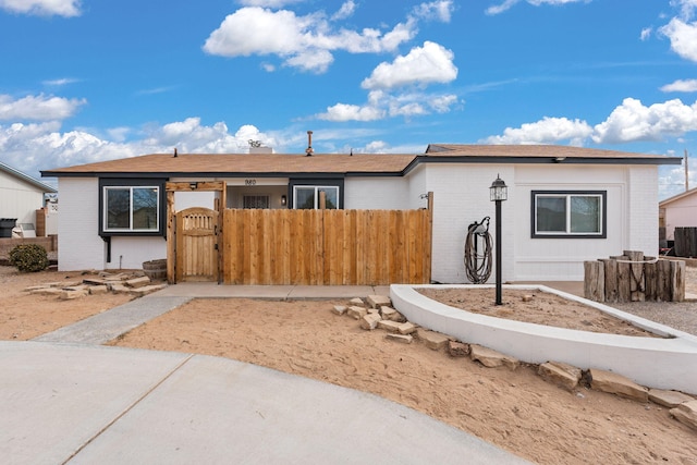 ranch-style home featuring a gate, fence, and brick siding