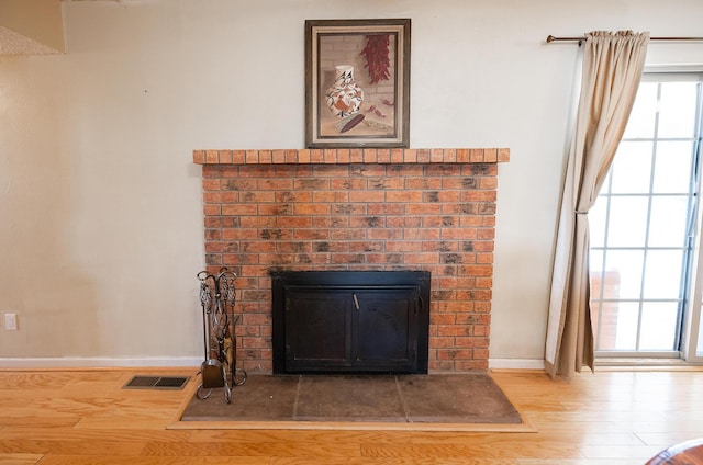 809 Kingman Ave, Grants, NM 87020 - details with wood finished floors, baseboards, visible vents, and a brick fireplace