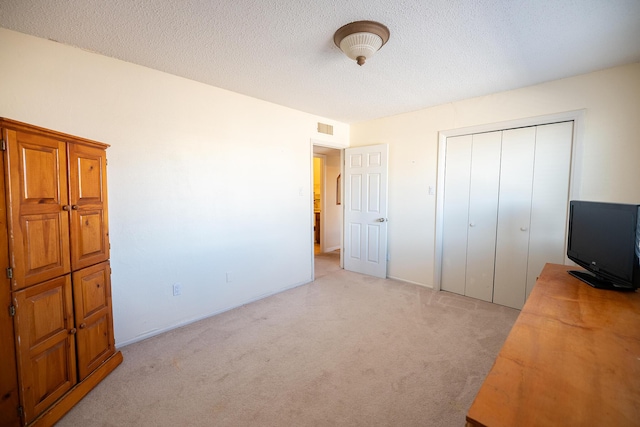 809 Kingman Ave, Grants, NM 87020 - unfurnished bedroom with visible vents, light carpet, a textured ceiling, and a closet