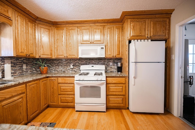 809 Kingman Ave, Grants, NM 87020 - kitchen with tasteful backsplash, white appliances, light wood-style floors, and brown cabinetry