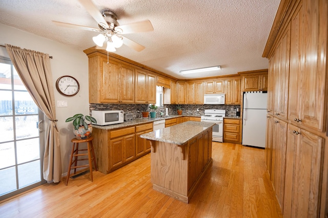 809 Kingman Ave, Grants, NM 87020 - kitchen featuring light wood finished floors, tasteful backsplash, white appliances, a textured ceiling, and plenty of natural light