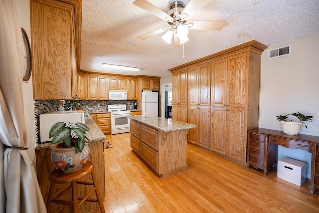 809 Kingman Ave, Grants, NM 87020 - kitchen featuring light wood-style floors, visible vents, a kitchen island, white appliances, and a textured ceiling