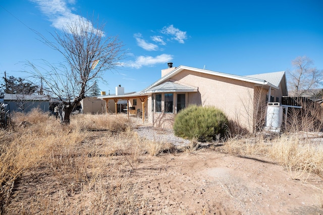 809 Kingman Ave, Grants, NM 87020 - rear view of property with fence, stucco siding, and a chimney