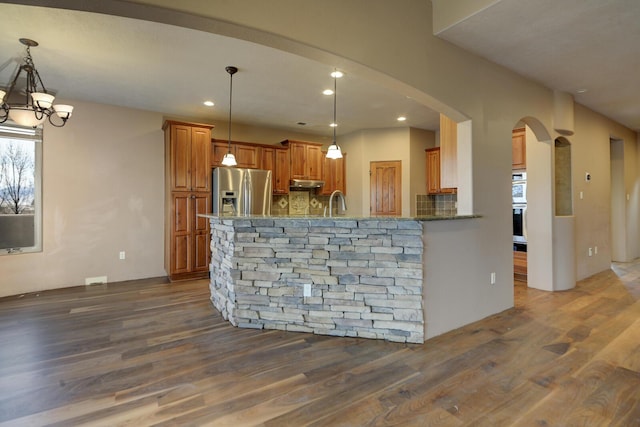 kitchen with stainless steel appliances, kitchen peninsula, dark hardwood / wood-style flooring, and decorative light fixtures