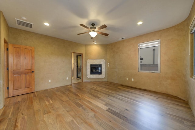 unfurnished living room with ceiling fan, a high end fireplace, and light hardwood / wood-style floors