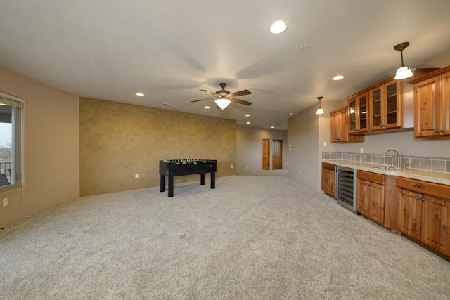 kitchen with pendant lighting, sink, wine cooler, light colored carpet, and ceiling fan