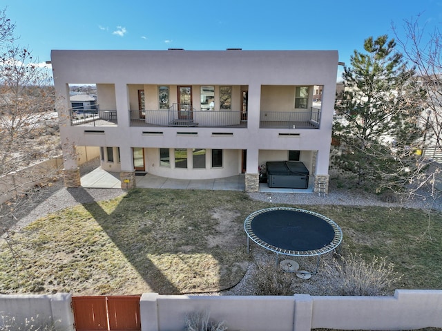 view of front of house featuring a balcony, a hot tub, a front lawn, and a trampoline