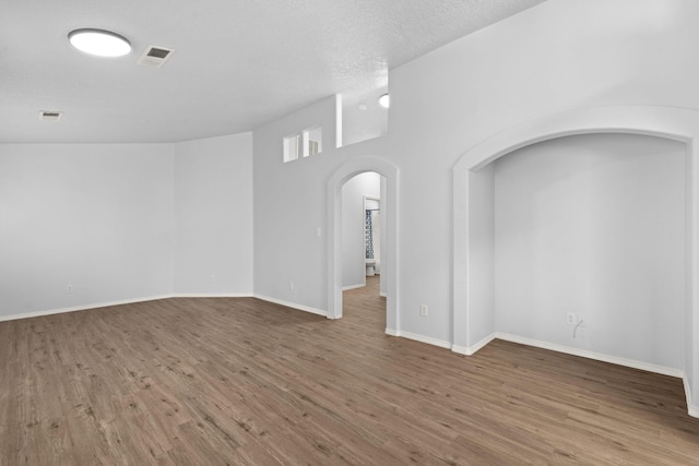 unfurnished room featuring hardwood / wood-style flooring, a high ceiling, and a textured ceiling