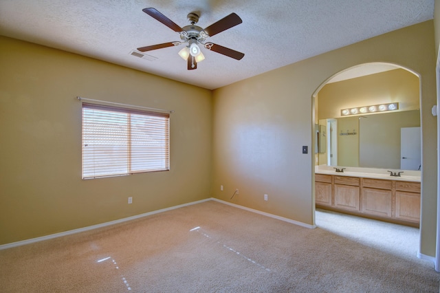 empty room featuring ceiling fan, light colored carpet, sink, and a textured ceiling