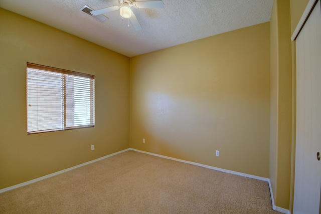 carpeted spare room featuring a textured ceiling and ceiling fan