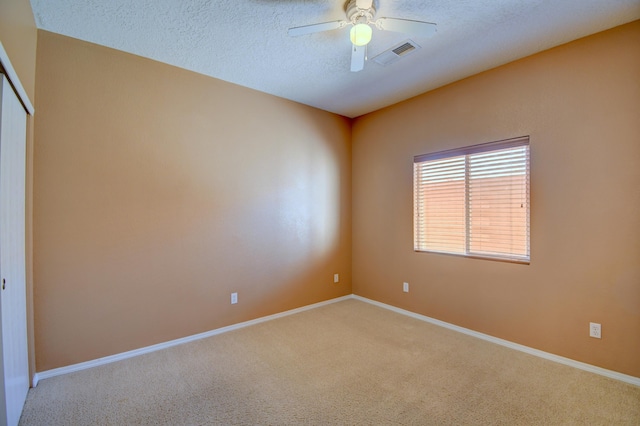 spare room with carpet, a textured ceiling, and ceiling fan