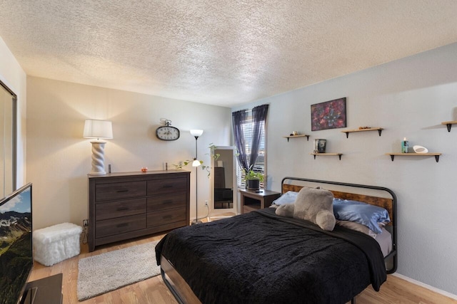 bedroom featuring light hardwood / wood-style flooring and a textured ceiling