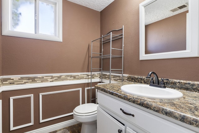 bathroom featuring vanity, toilet, and a textured ceiling