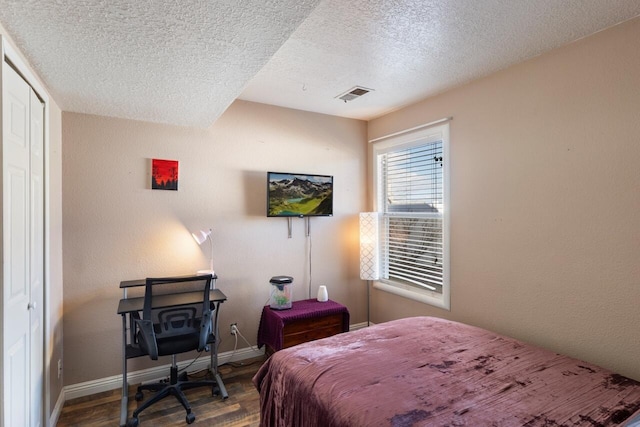 bedroom featuring hardwood / wood-style floors, a textured ceiling, and a closet