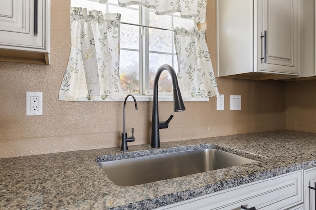 kitchen featuring sink, white cabinets, and dark stone counters