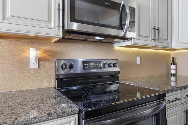 kitchen featuring range with electric stovetop, white cabinetry, tasteful backsplash, and dark stone countertops