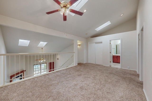 empty room featuring light carpet, a skylight, high vaulted ceiling, and ceiling fan