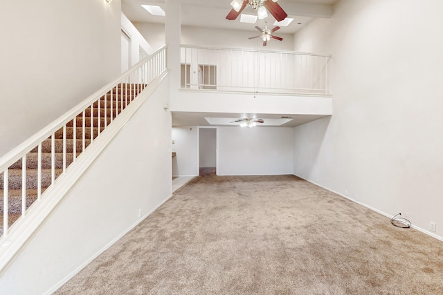 unfurnished living room featuring ceiling fan, carpet floors, and a towering ceiling