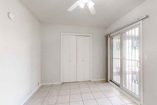 interior space with access to outside, a closet, ceiling fan, and light tile patterned flooring