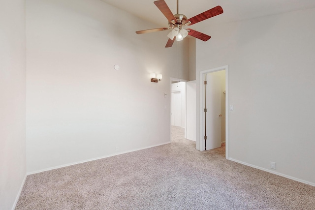 carpeted empty room with ceiling fan and high vaulted ceiling