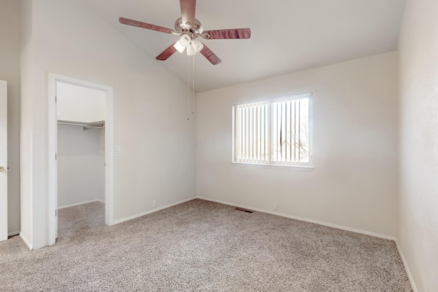 unfurnished bedroom with ceiling fan, vaulted ceiling, light carpet, a walk in closet, and a closet