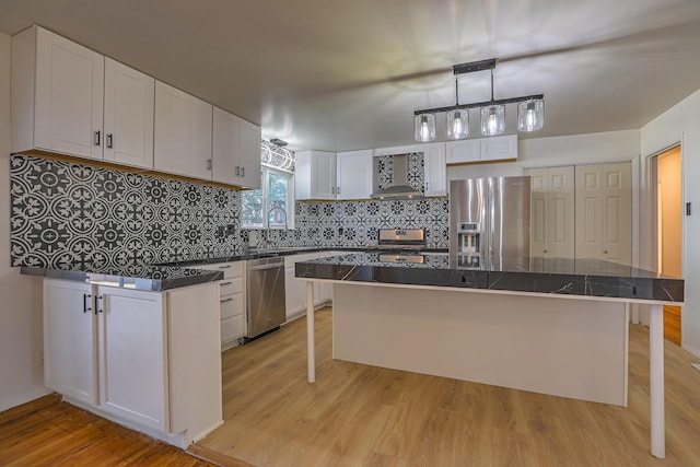 kitchen featuring white cabinetry, a kitchen island, stainless steel appliances, light hardwood / wood-style floors, and wall chimney range hood