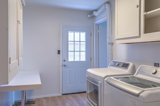 washroom with washer and dryer, cabinets, and light wood-type flooring