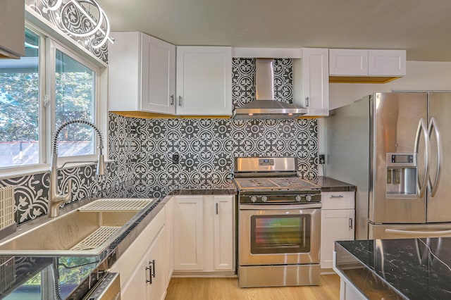 kitchen with sink, white cabinetry, wall chimney range hood, stainless steel appliances, and backsplash