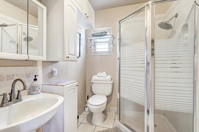 bathroom with a shower with shower door, sink, tile patterned floors, and toilet