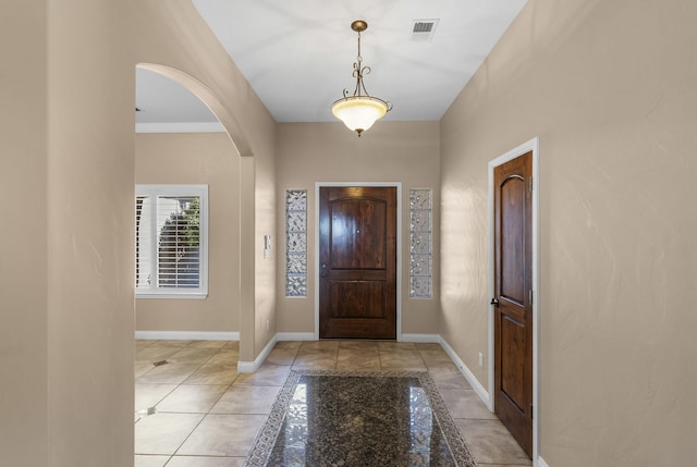 foyer featuring light tile patterned floors and crown molding